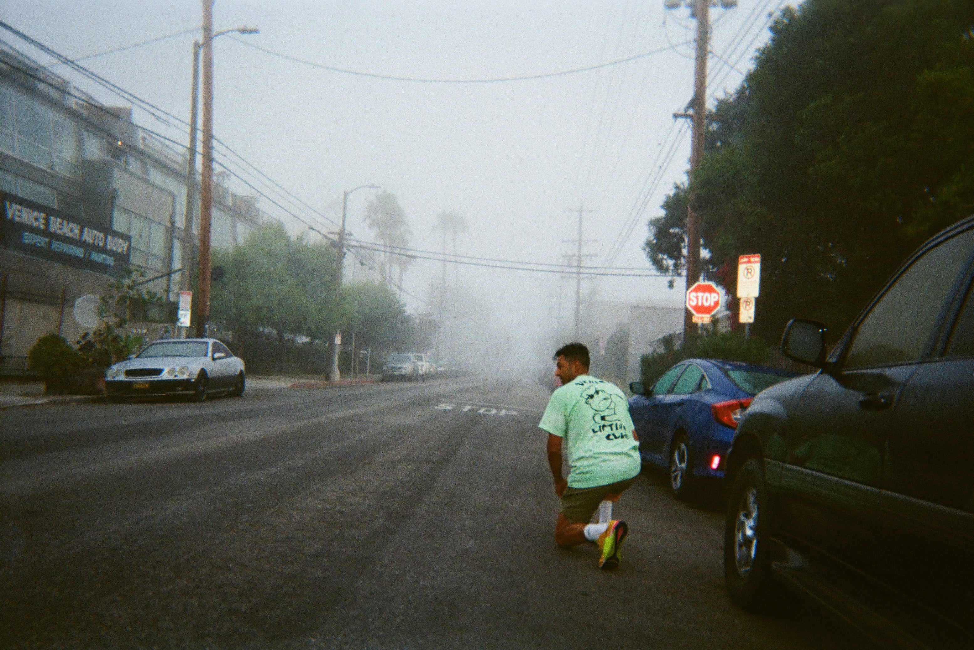 Venice Lifting Club t shirt, man tying shoe in street